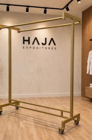 Arara Dourada de Roupa Dupla Reforçada com Rodas para peso de 1.7 metros de altura por 1.5 metros de largura, com pintura eletrostática fosca e rodinhas de silicone, posicionada em showroom elegante com o logotipo da HAJA Expositores ao fundo.