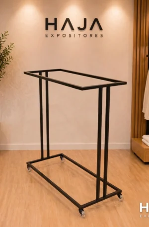 Arara Preta de Roupa Dupla com Rodas de 1.7 metros de altura por 1.5 metros de largura, com pintura eletrostática preta fosca e rodinhas de silicone, posicionada em showroom elegante com o logotipo da HAJA Expositores ao fundo.